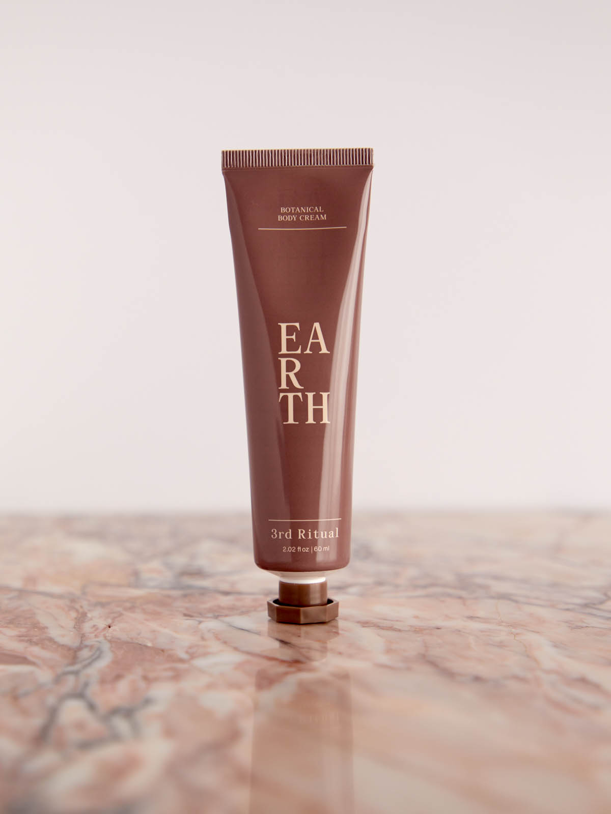 Earth Botanical Body Cream on pink marble