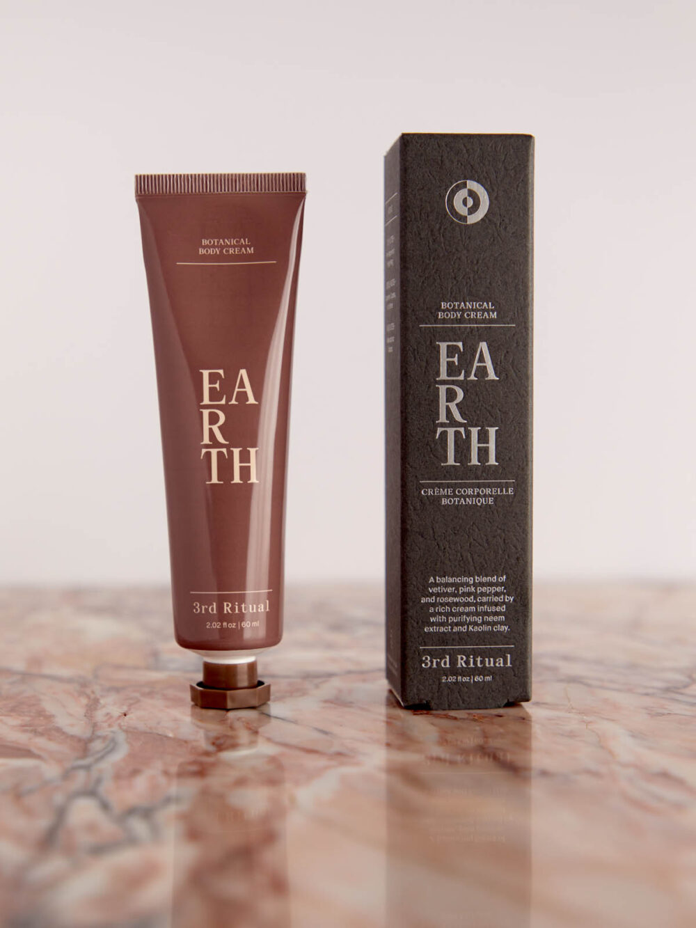 Earth Botanical Body Cream and box on pink marble