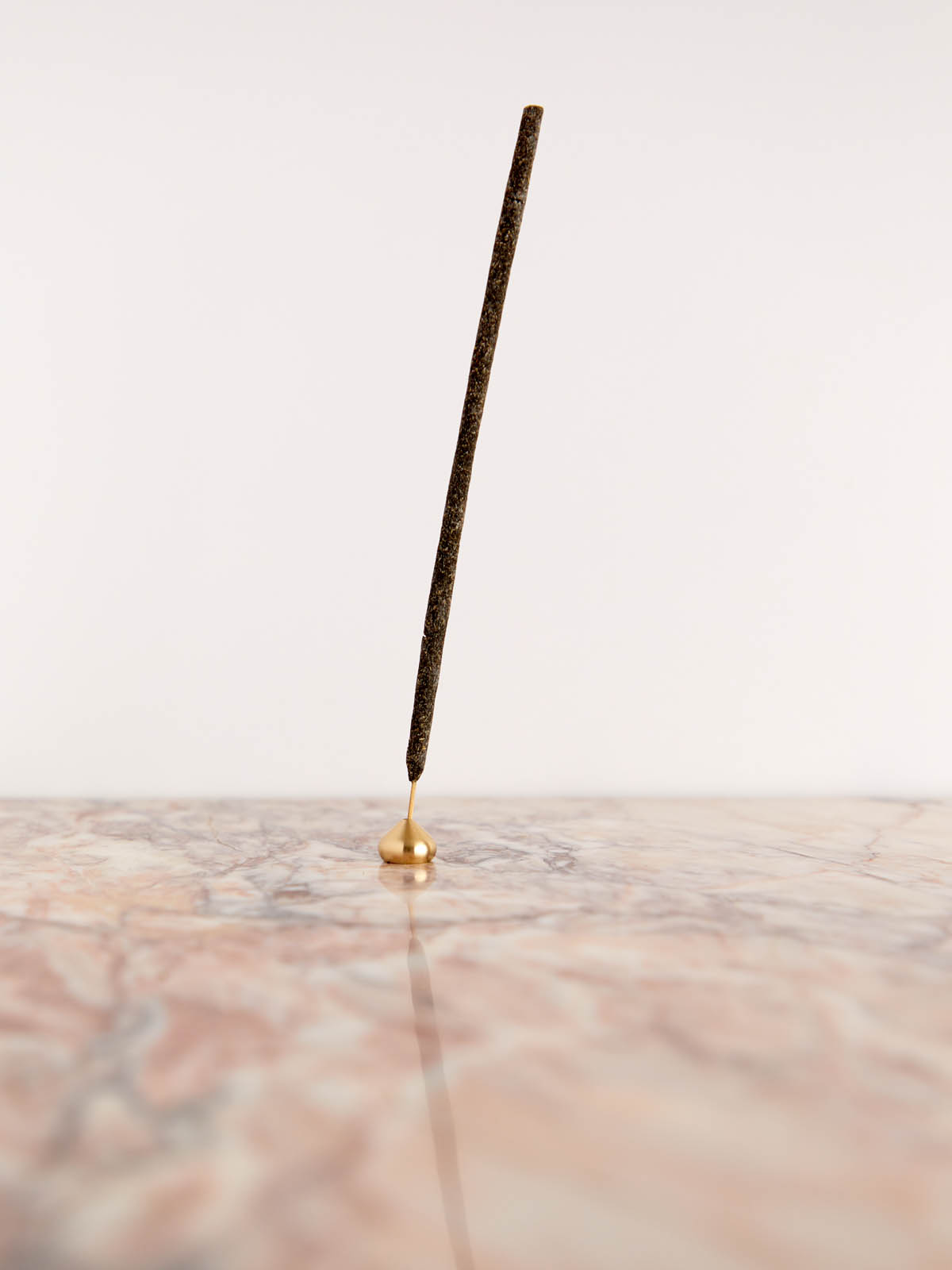 Medium Brass Water Drop Incense Holder by Cedar & Myrrh with incense on pink marble