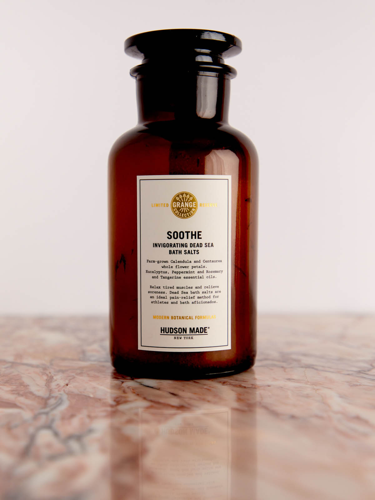 Soothe - Invigorating Dead Sea Salts in glass bottle on pink marble by Hudson Made