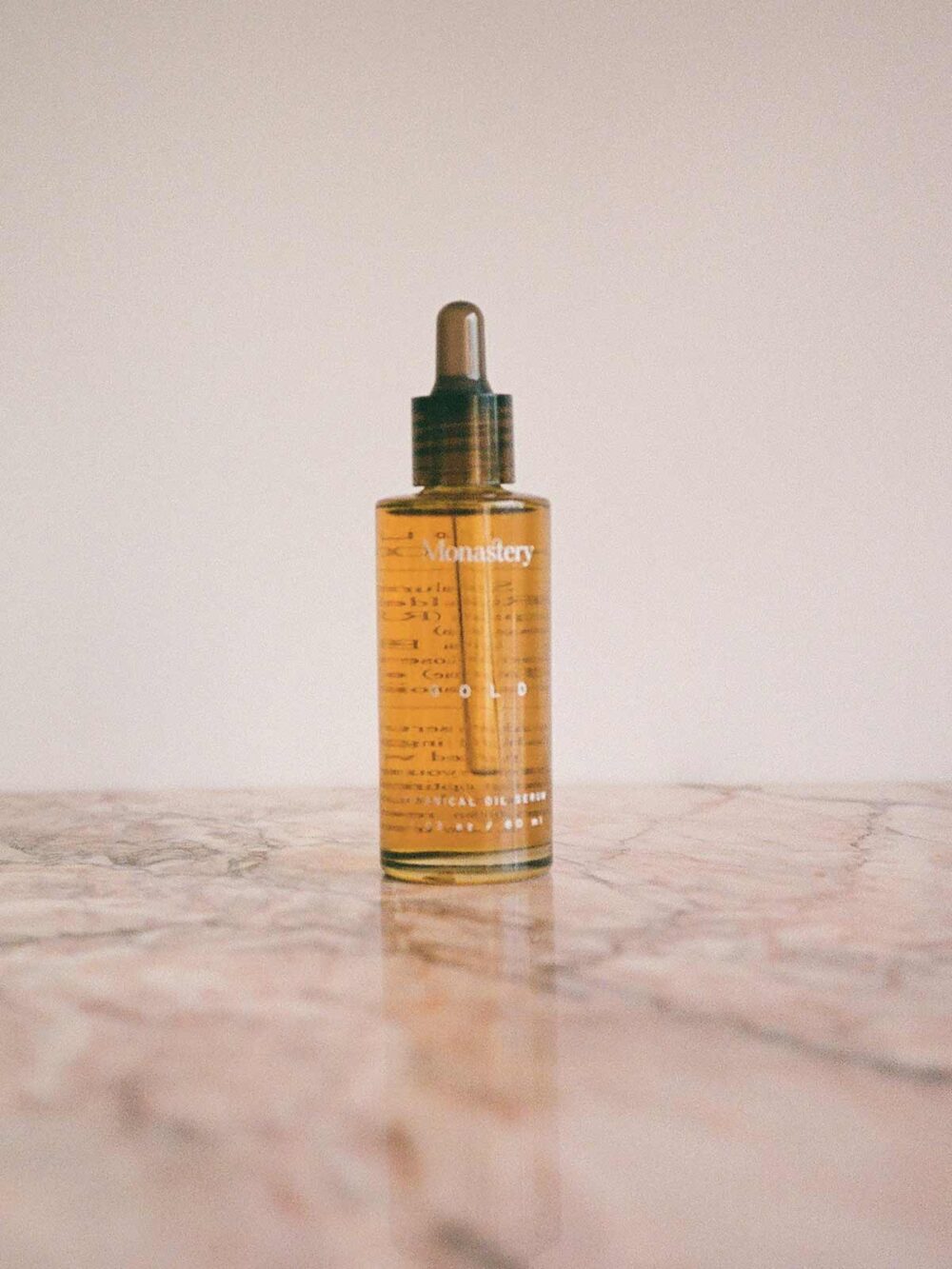 Gold Botanical Oil Serum bottle on pink marble by Monastery Made